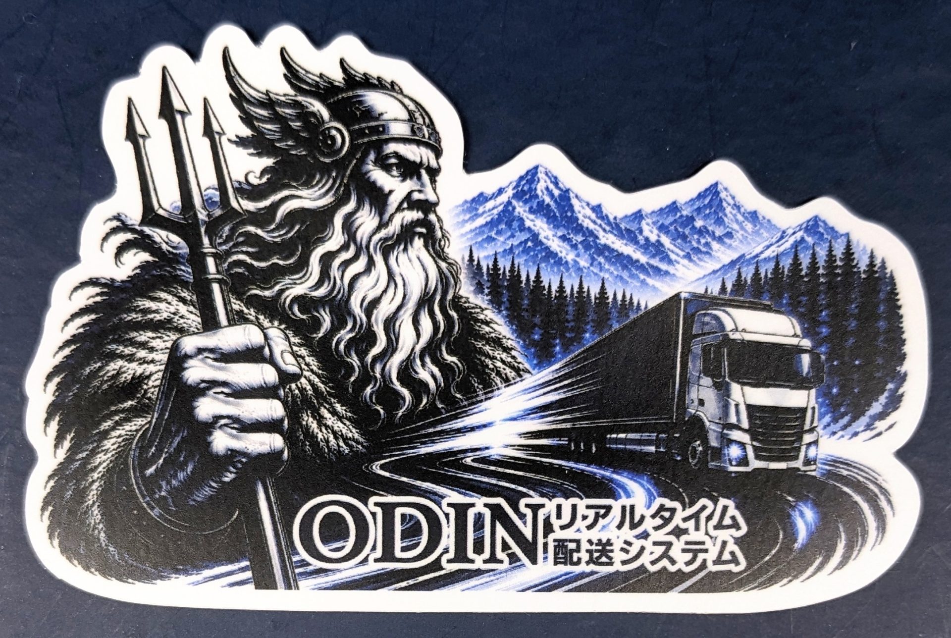 Odin-like bearded figure with a staff, snow-capped mountains behind, a truck on a winding road, and the word ODIN at the bottom.